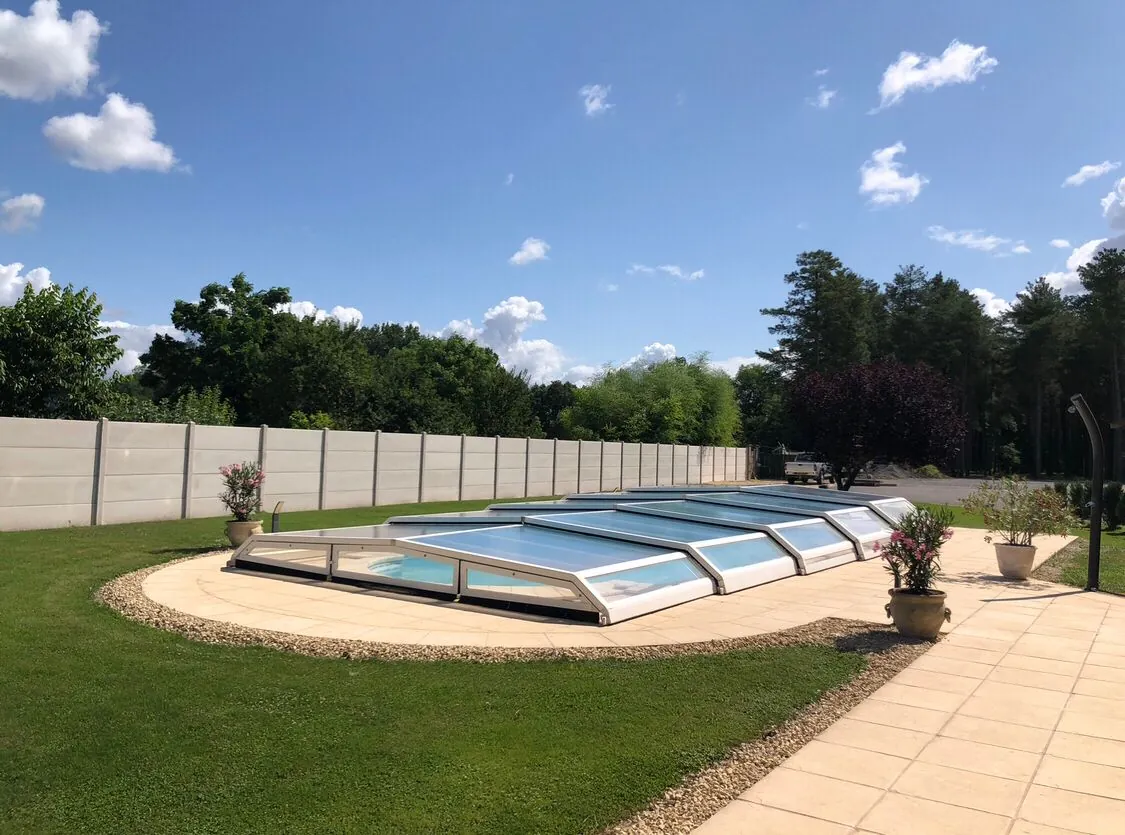Abri de piscine télescopique bas, ouvert sur le jardin